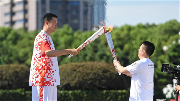 8月1日，火炬手王治郅（左）与火炬手肖东交接火炬。 新华社记者万象摄